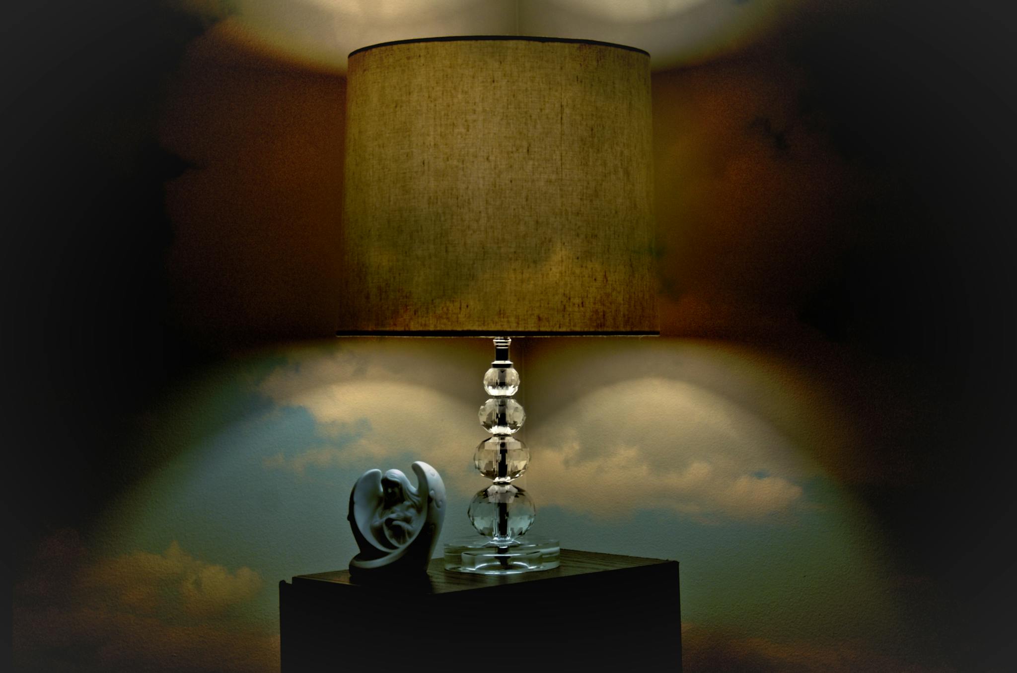 A stylish table lamp with a unique sculpture on a dark wooden surface, creating a cozy ambiance.